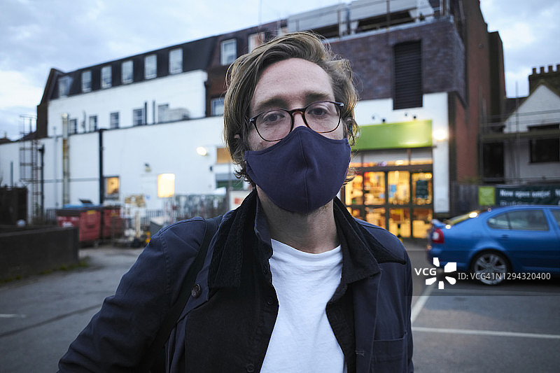 疫情期间男人戴着口罩在商店外购物图片素材