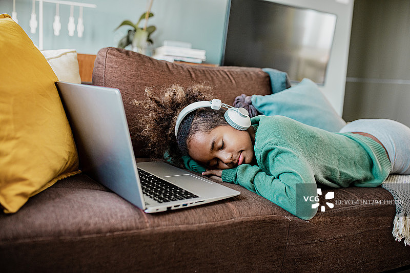 可爱的小非裔美国女孩在使用笔记本电脑时睡着了图片素材