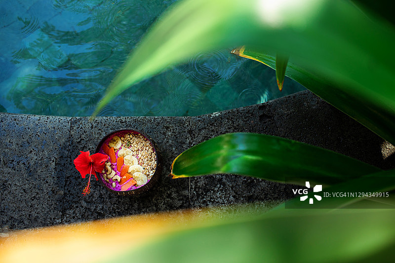 新鲜热带有机水果冰沙，椰子碗配吸管，亚洲度假村泳池边的夏日草帽。火龙果和香蕉纯素碗，配木瓜、谷物坚果和种子。夏日氛围。图片素材