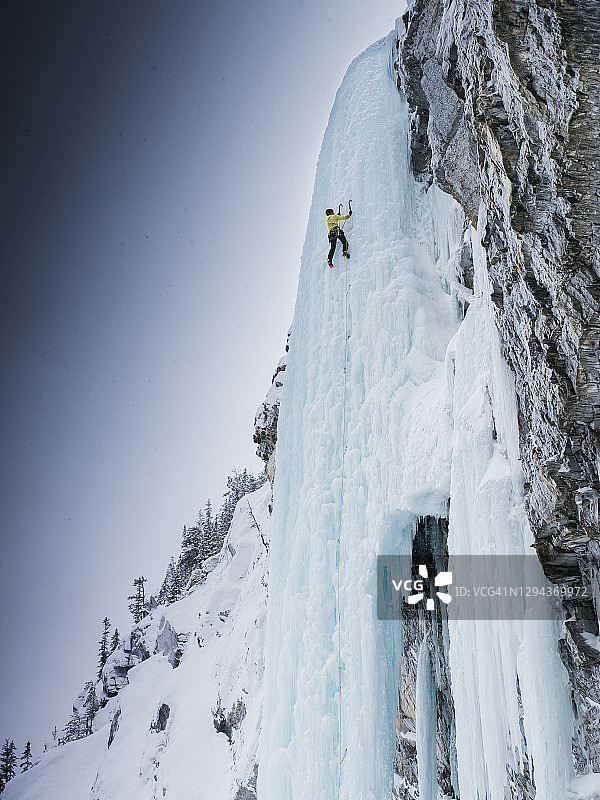 仰望在优鹤国家公园陡峭冰冻瀑布上攀冰的登山者图片素材