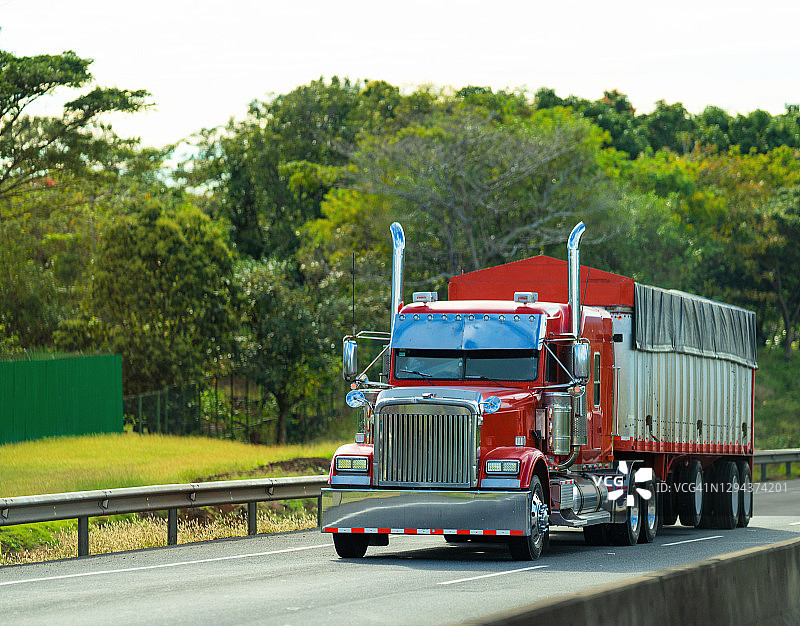 在哥斯达黎加高速公路上行驶的红色半挂卡车图片素材