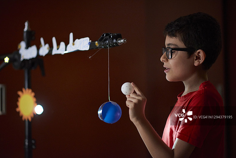 封锁期间在家上学的男孩（8-9岁）正在做关于太阳相位的演示图片素材