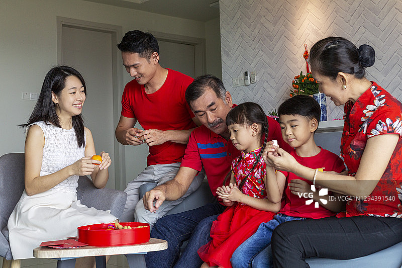 微笑的一家人坐在沙发上庆祝中国新年图片素材