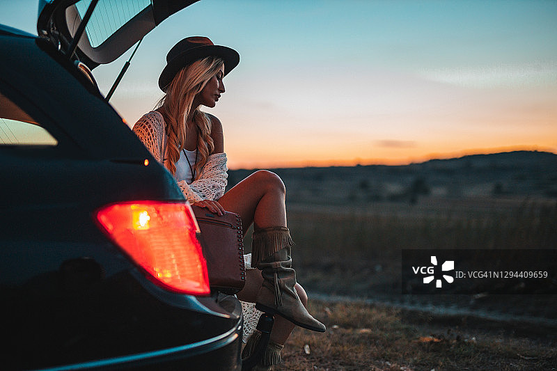 女人坐在汽车后备箱里，享受着大自然的夜晚图片素材