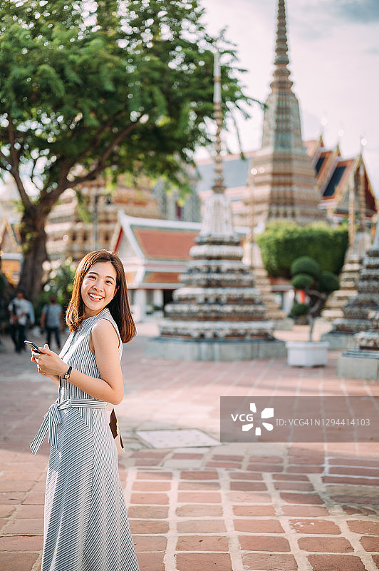 亚洲游客在曼谷卧佛寺/郑王庙旅游拍照，上传社交媒体，疫情后的新常态旅游图片素材