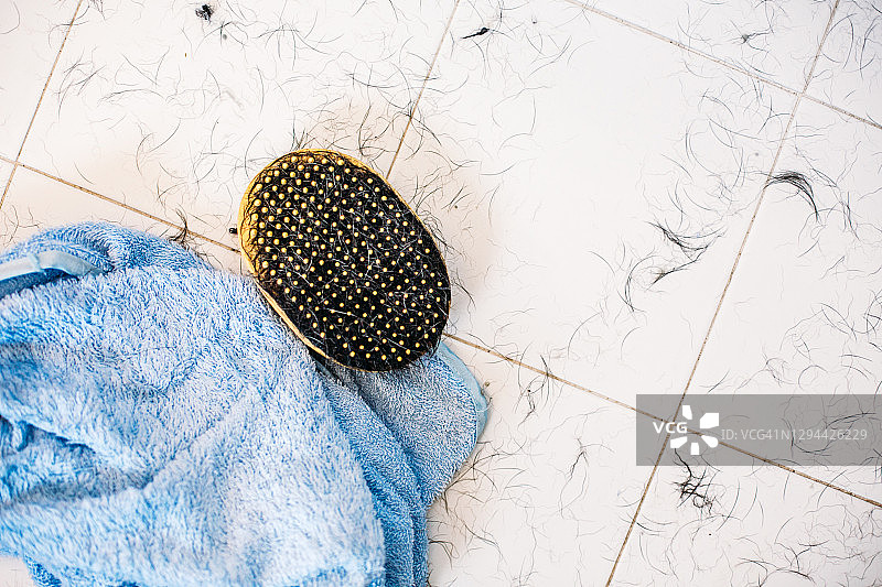 白色浴室地板上的蓝色毛巾和黄色橡胶刷图片素材