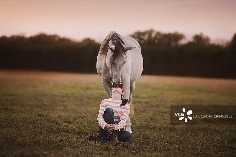 坐在马前，深情地望着马的少女图片素材