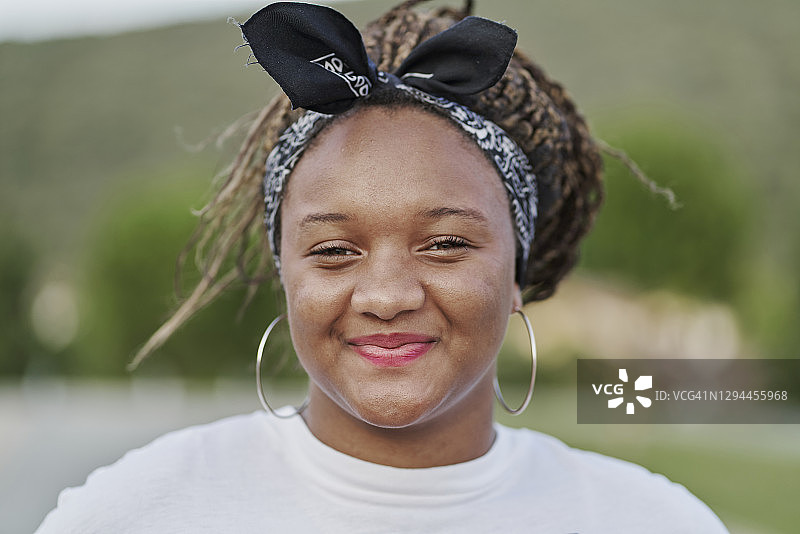 一个戴着发带的黑人女孩拿着她的脏辫的肖像图片素材