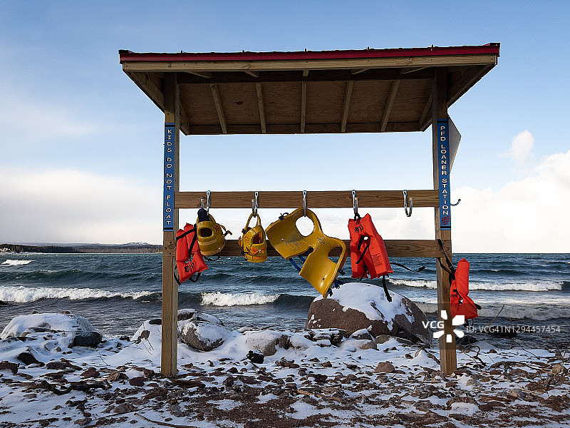 鲜艳橙色救生衣挂在波涛汹涌的海岸边图片素材