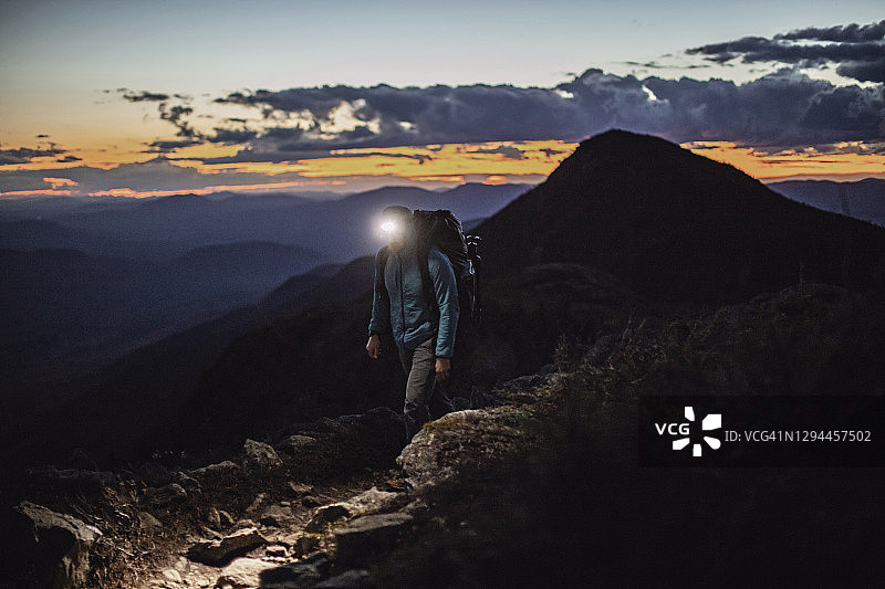 徒步者在黄昏时分站在山顶，头灯照亮，缅因州比格洛图片素材