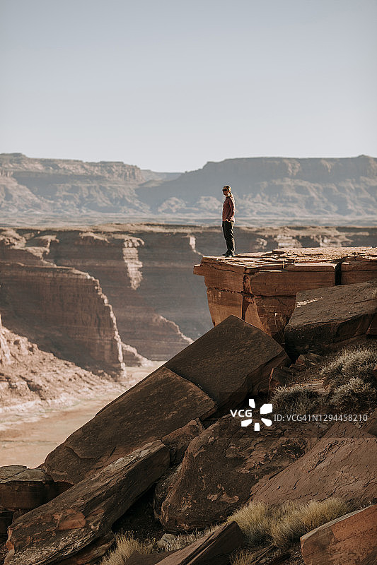 女人站在犹他州海特高耸悬崖边，俯瞰沙漠图片素材