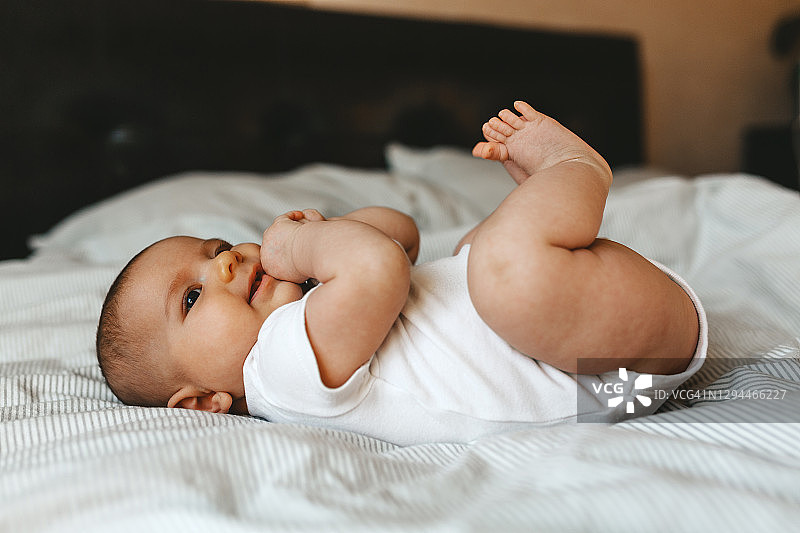 可爱的白人宝宝躺在床上看着镜头，快乐的童年生活图片素材