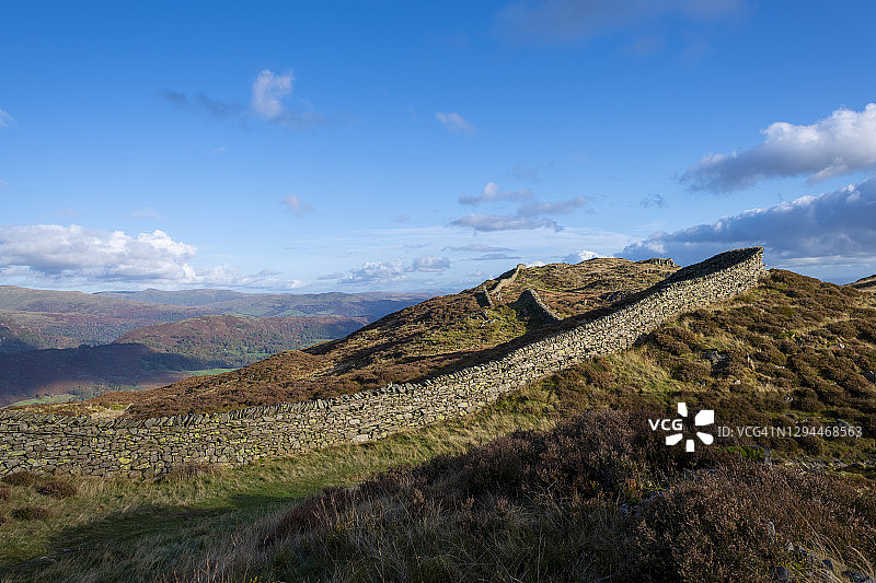 在湖区 Lingmoor Fell 顶部，干燥的石墙沿着起伏的山丘延伸图片素材