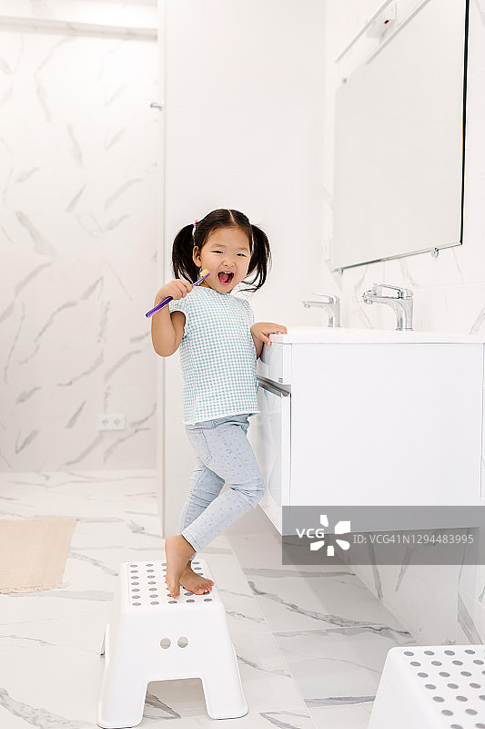 站在浴室水槽旁刷牙的亚洲小女孩图片素材