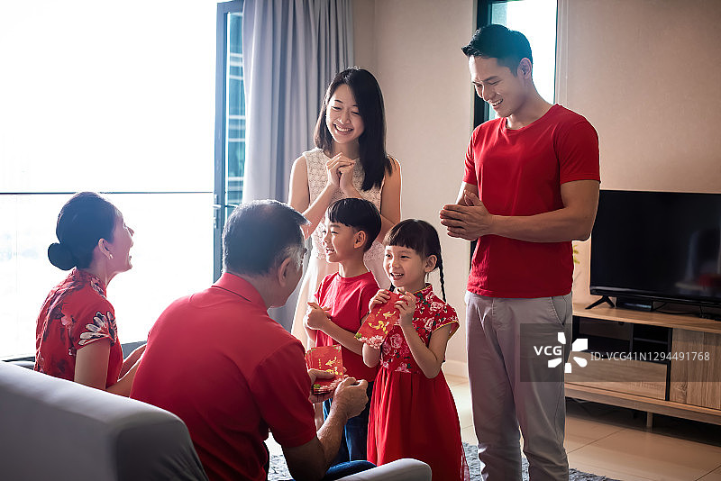 快乐喜悦的华人祖父母在中国新年第一天在家给孙子孙女红包图片素材