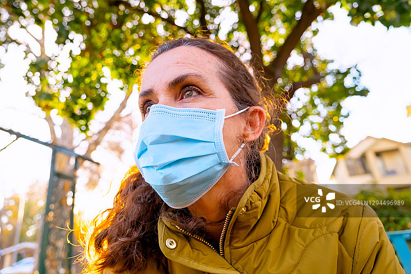 中年妇女戴着防护面罩，看向远方图片素材