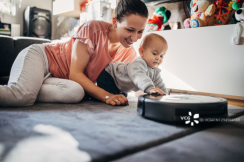 母亲和宝宝儿子一起玩扫地机器人图片素材