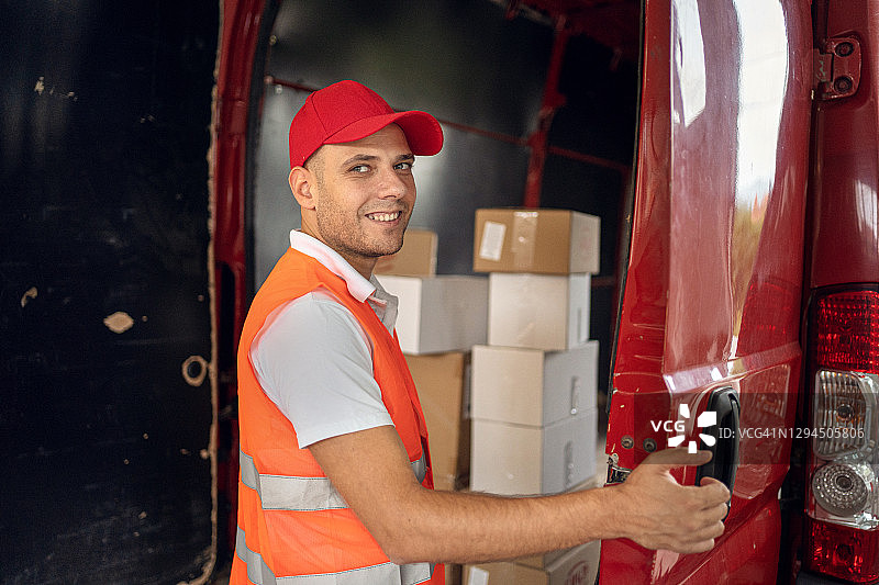 快递员站在装满包裹的货车前图片素材