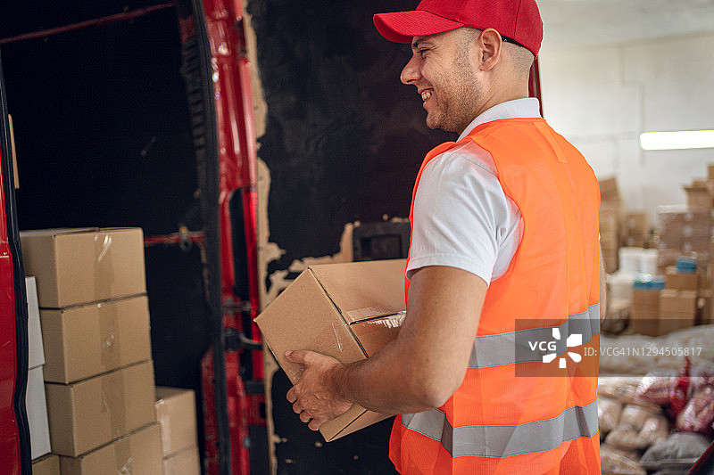 快递员站在装满包裹的货车前图片素材