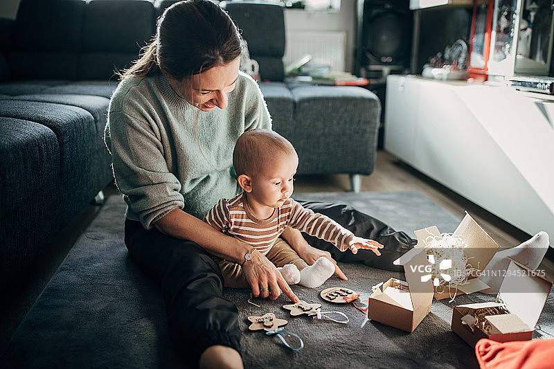 快乐的母亲和儿子在家一起打开礼物图片素材
