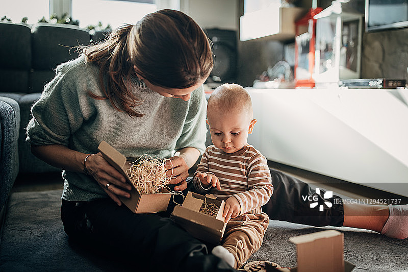 年轻的母亲和男婴一起打开礼物图片素材