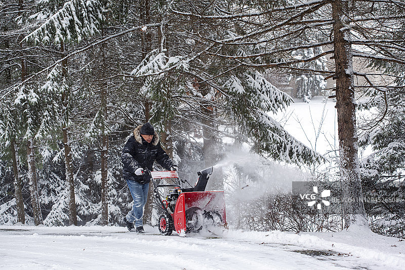 男人使用吹雪机清理车道图片素材