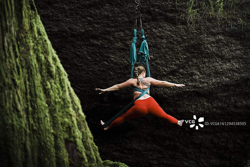 女子在昏暗的森林中表演空中瑜伽图片素材