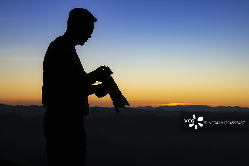 在峰顶岩石上的专业摄影师剪影图片素材