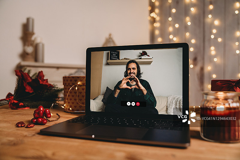 年轻男人在视频通话中用手比心，庆祝情人节图片素材