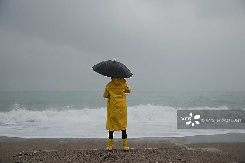 沙滩风暴和穿着黄色雨衣的男人：风暴、雨、海岸、巨浪图片素材