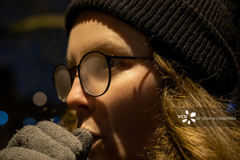 女孩用呼吸温暖双手，眼镜都蒙上了雾气图片素材