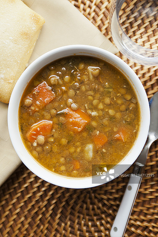 蔬菜糙扁豆汤碗配面包、水杯和餐巾图片素材