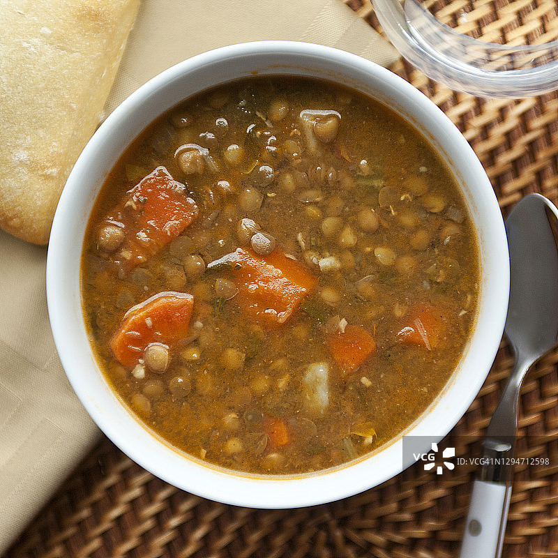 蔬菜糙扁豆汤碗配面包、水杯和餐巾图片素材