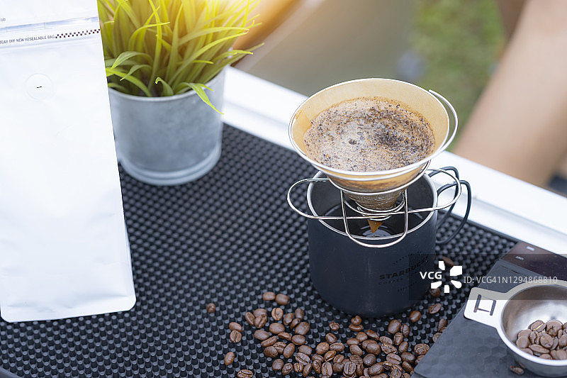 户外用滤纸将热水倒入研磨咖啡粉中制作滴滤咖啡的特写图片素材