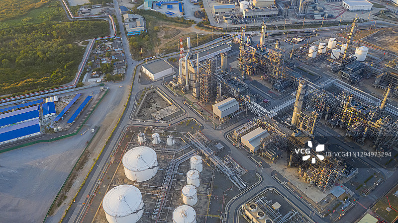 飞越炼油厂，管道和烟囱林立。黄昏时分，阴沉天空下的石化厂航拍图片素材