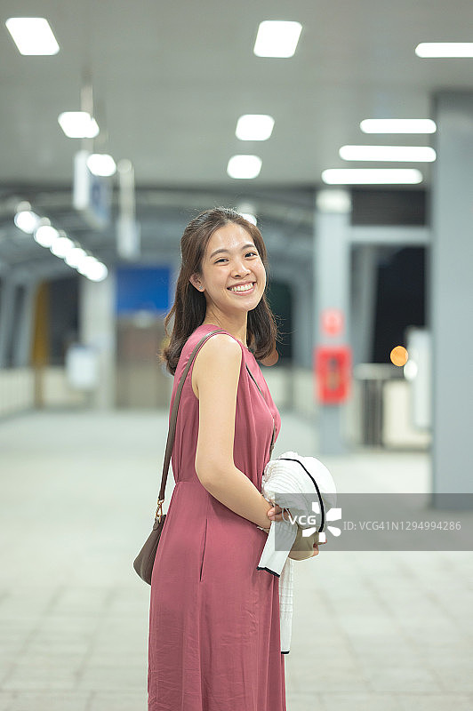 快乐的亚洲商务女性在曼谷工作，穿着休闲服装乘坐公共交通工具，夜间乘坐轻轨捷运地铁图片素材