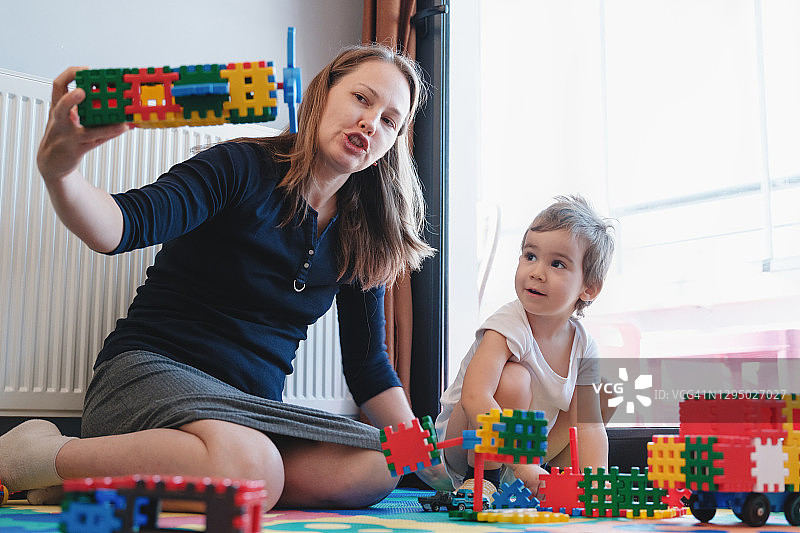 快乐的母亲和幼儿儿子在家玩玩具图片素材