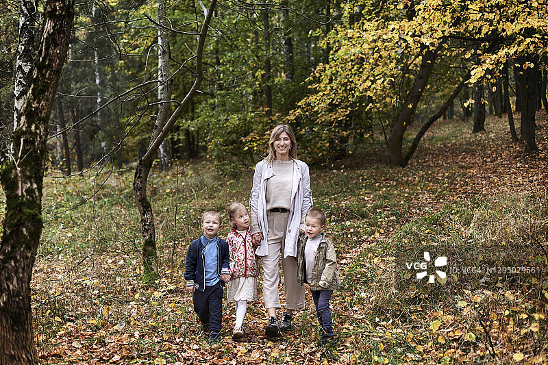 母亲和三胞胎在秋天的森林里图片素材