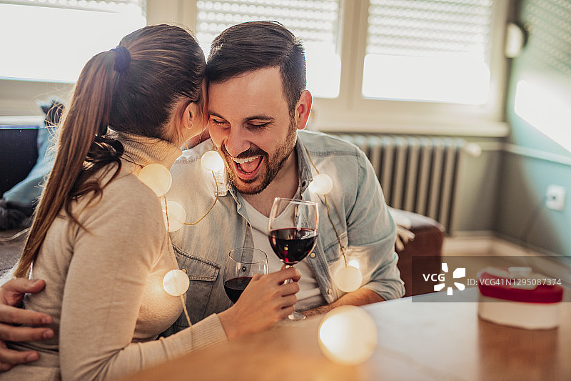 年轻情侣在家中庆祝情人节，品尝美酒图片素材