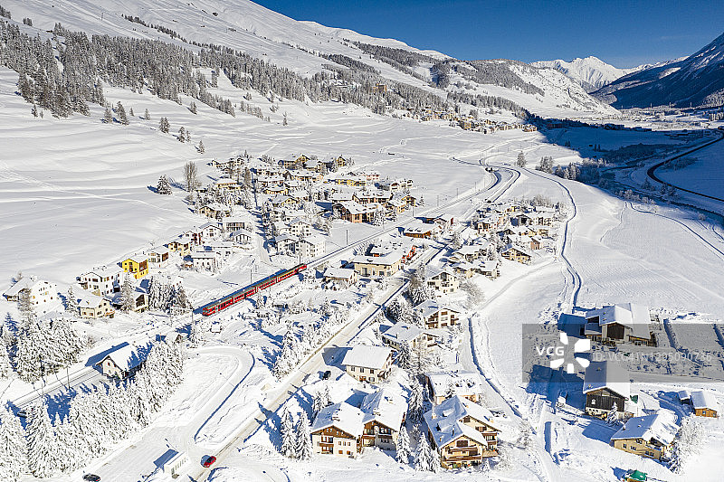 被白雪覆盖的阿尔卑斯村庄中的伯尼纳快车 - 瑞士图片素材