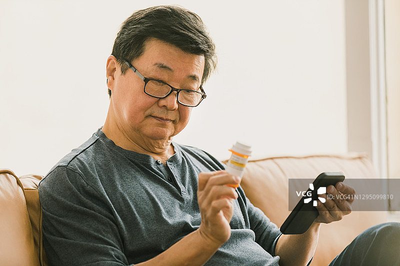 年长的男人阅读药品标签上的说明图片素材