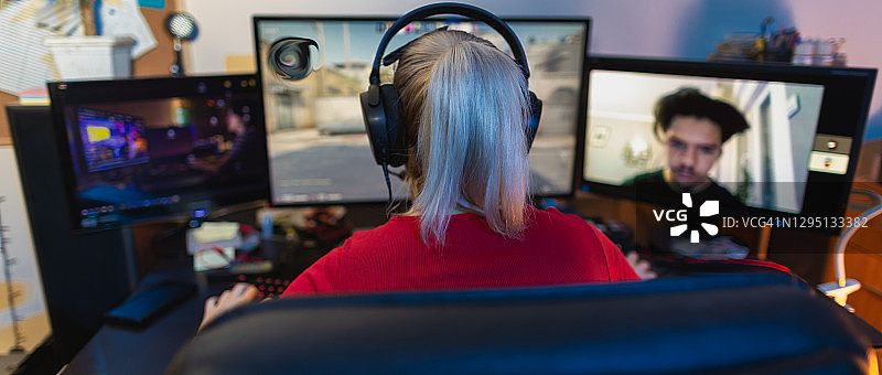 在黑暗房间里用台式电脑玩多人游戏的少女图片素材