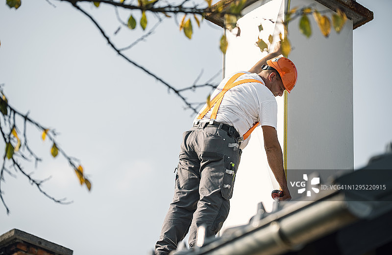 屋顶工人测量屋顶上的烟囱图片素材