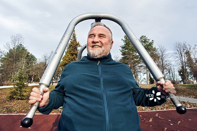 年长的男人在户外健身房的器械上锻炼图片素材