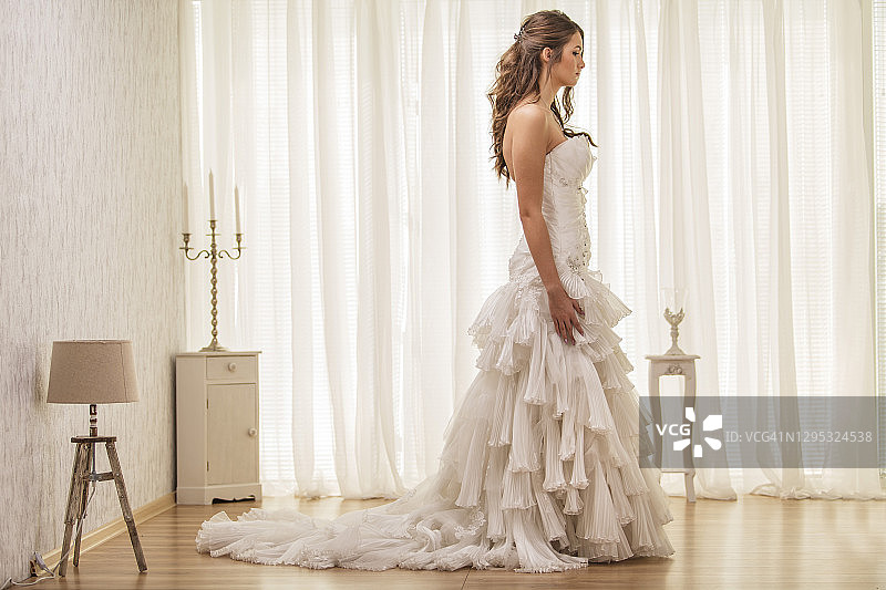 穿着婚纱沉思的新娘的侧视图图片素材