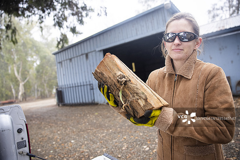 年轻女人往卡车上装木头图片素材