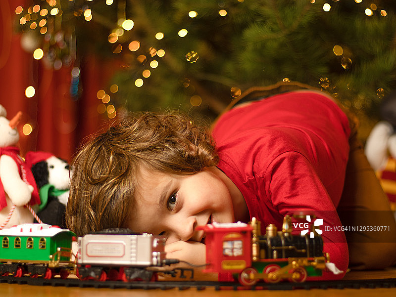 儿童在圣诞树下玩玩具火车图片素材