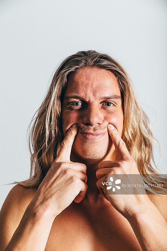 情绪的表达，面部表情。表演，表演，表演试镜。躯干。一个长头发的白人。假装开心，假笑，不真诚，虚伪。图片素材