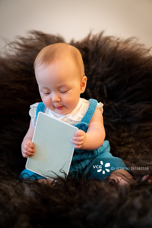 宝宝坐在挪威奥斯陆的黑色毛绒地毯上图片素材