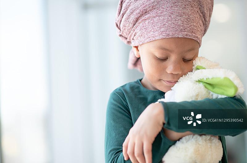 拥抱泰迪熊的患癌年轻女孩图片素材